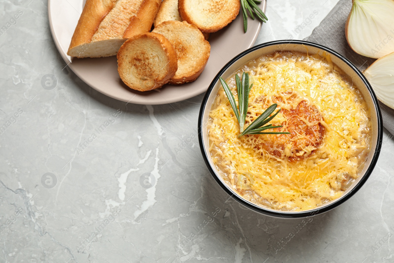 Photo of Tasty homemade french onion soup served on grey marble table, flat lay. Space for text