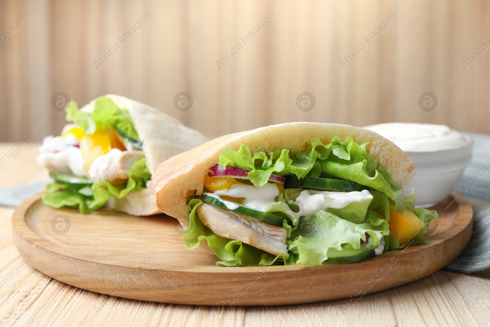 Photo of Delicious pita sandwiches with chicken breast and vegetables on wooden table, closeup