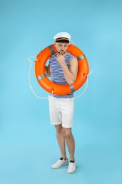 Photo of Sailor with orange ring buoy on light blue background