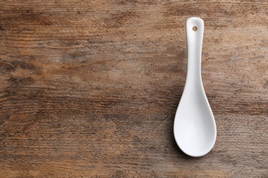 Photo of Clean empty miso spoon on wooden background, top view. Space for text