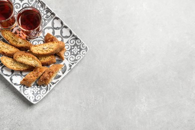 Tasty cantucci and glasses of liqueur on light table, top view with space for text. Traditional Italian almond biscuits