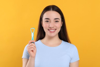 Photo of Happy woman with tongue cleaner on yellow background