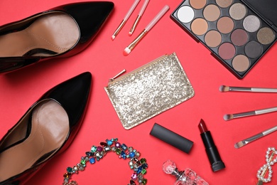 Flat lay composition with women's shoes, cosmetics and accessories on red background