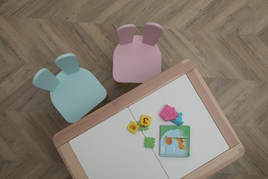 Photo of Small table and chairs with bunny ears in children's room, top view