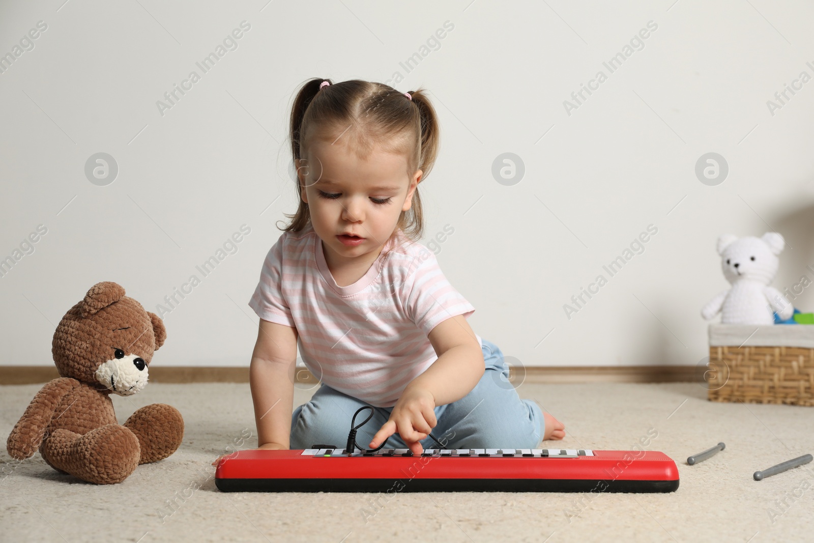 Photo of Cute little girl playing with toy piano at home