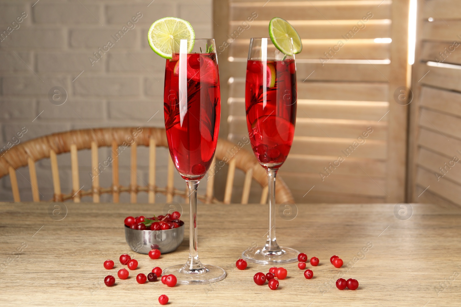 Photo of Tasty cranberry cocktail with rosemary and lime in glasses on wooden table