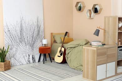 Stylish teenager's room interior with comfortable bed and guitar