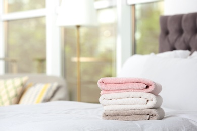 Stack of soft clean terry towels on bed. Space for text