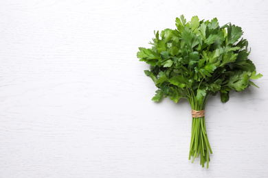 Photo of Bunch of fresh green parsley on white wooden table, top view. Space for text