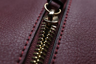 Photo of Burgundy leather fabric with zipper as background, closeup