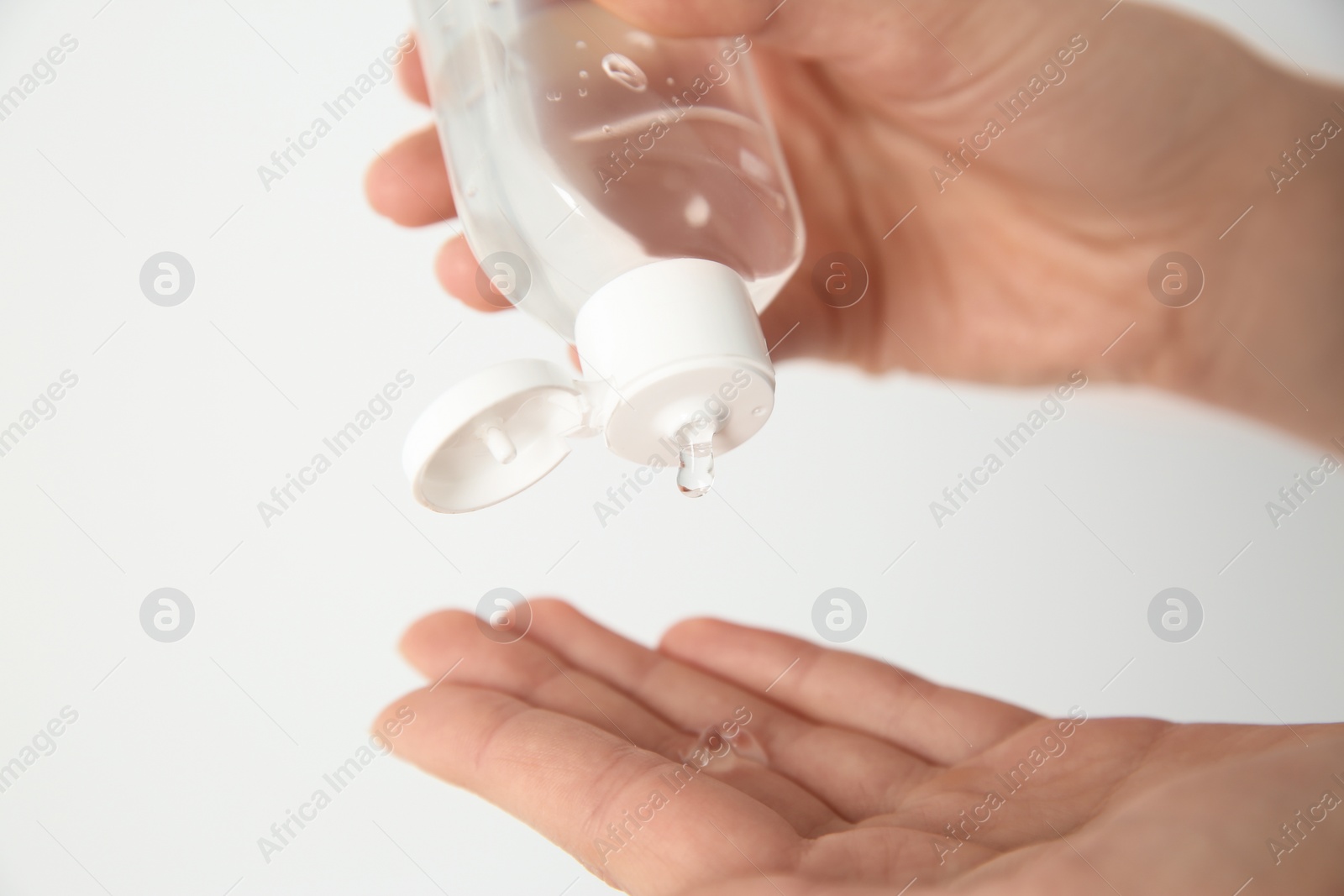 Photo of Woman applying antiseptic gel on light background, closeup