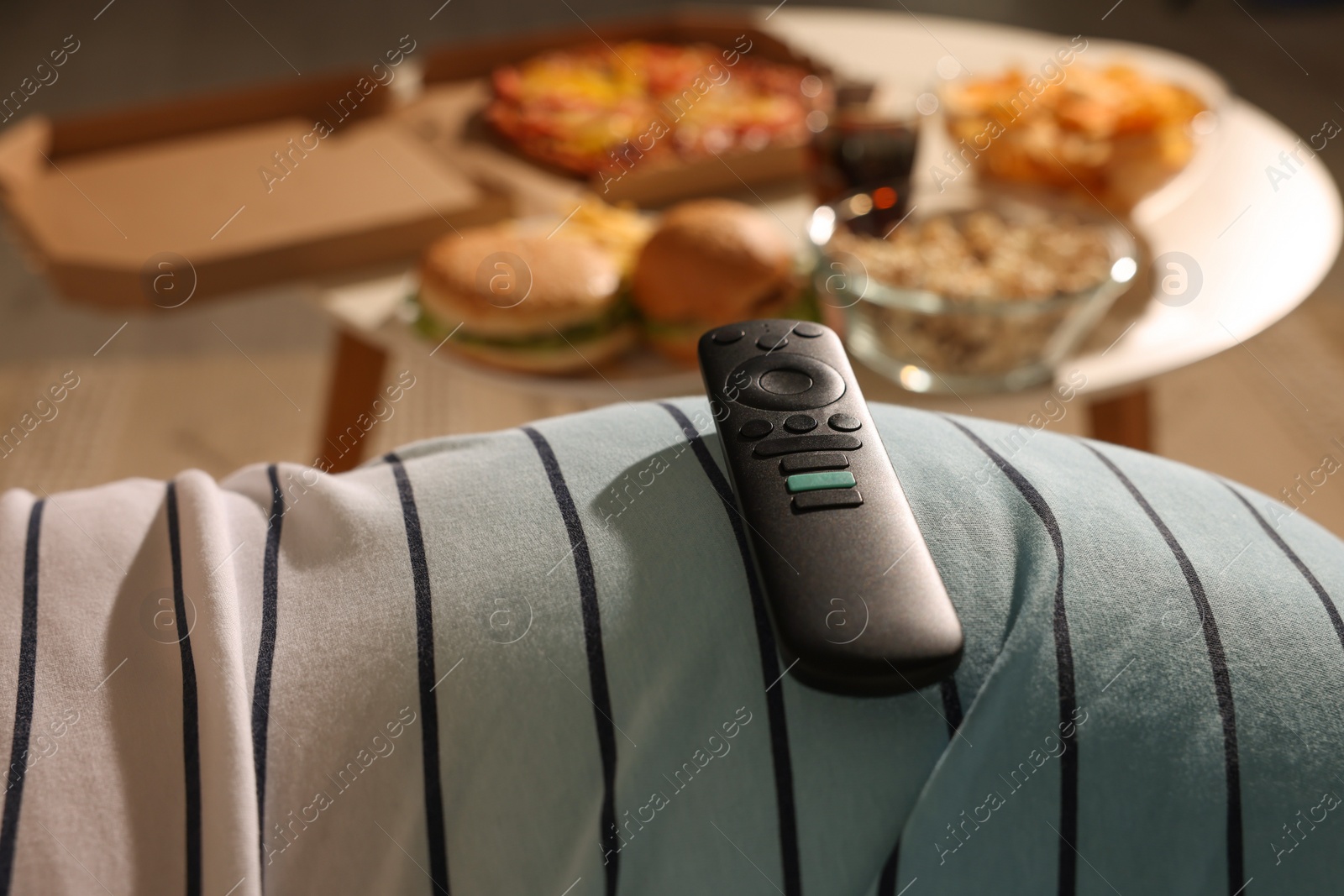 Photo of Overweight man with tv remote control on belly at home, closeup
