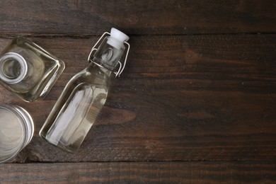 Photo of Vinegar in bottles and glass on wooden table, flat lay. Space for text