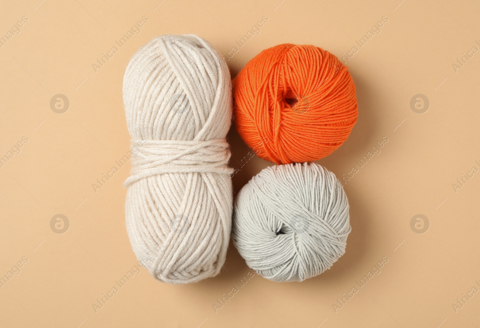 Photo of Soft woolen yarns on beige background, flat lay