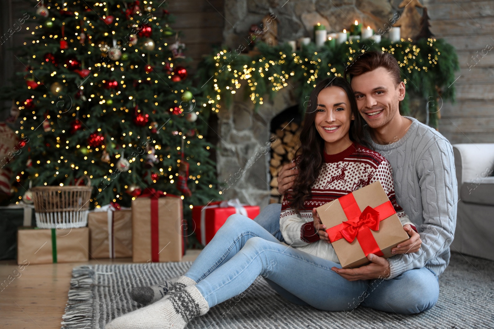 Photo of Happy couple with gift box in living room decorated for Christmas