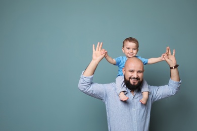 Portrait of dad and his little son on color background