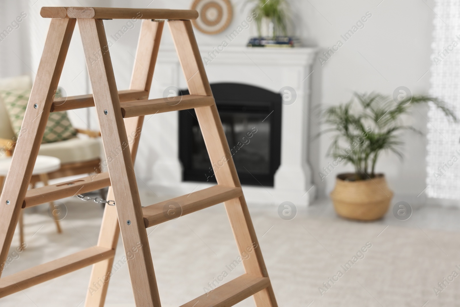 Photo of Wooden folding ladder in stylish living room. Space for text