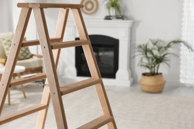 Photo of Wooden folding ladder in stylish living room. Space for text