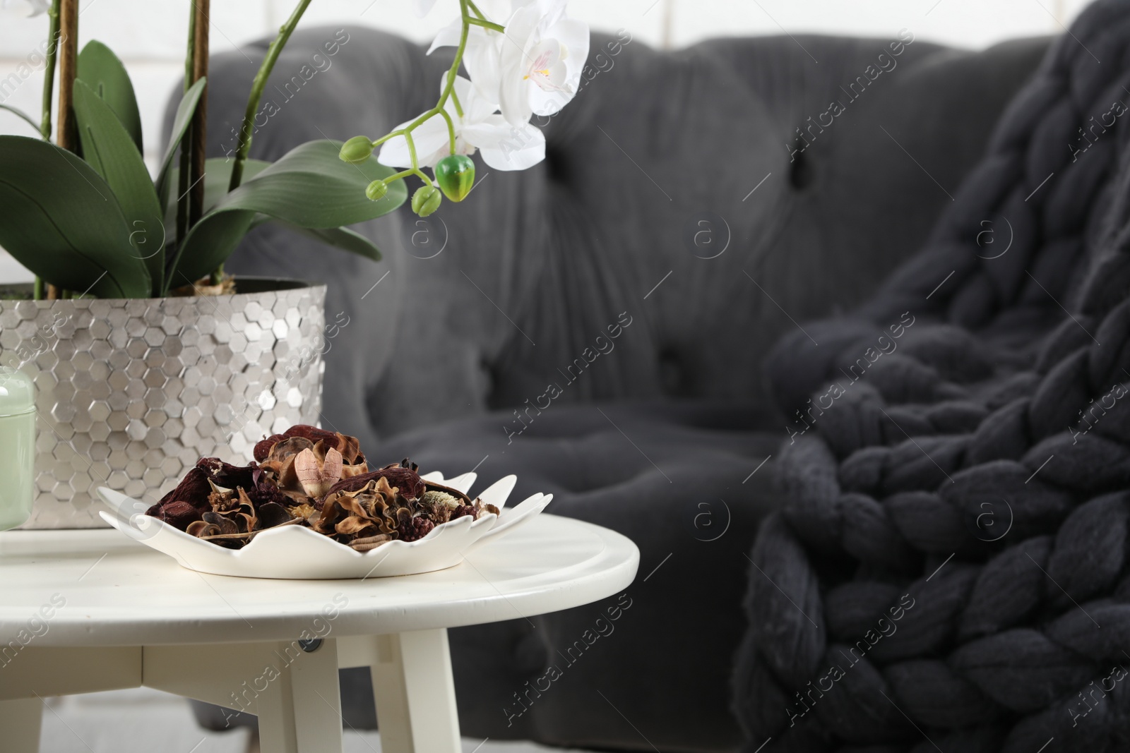 Photo of Aromatic potpourri of dried flowers in plate and beautiful houseplant on white table indoors. Space for text