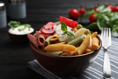 Photo of Delicious vegetable pasta with sour cream dressing on black wooden table