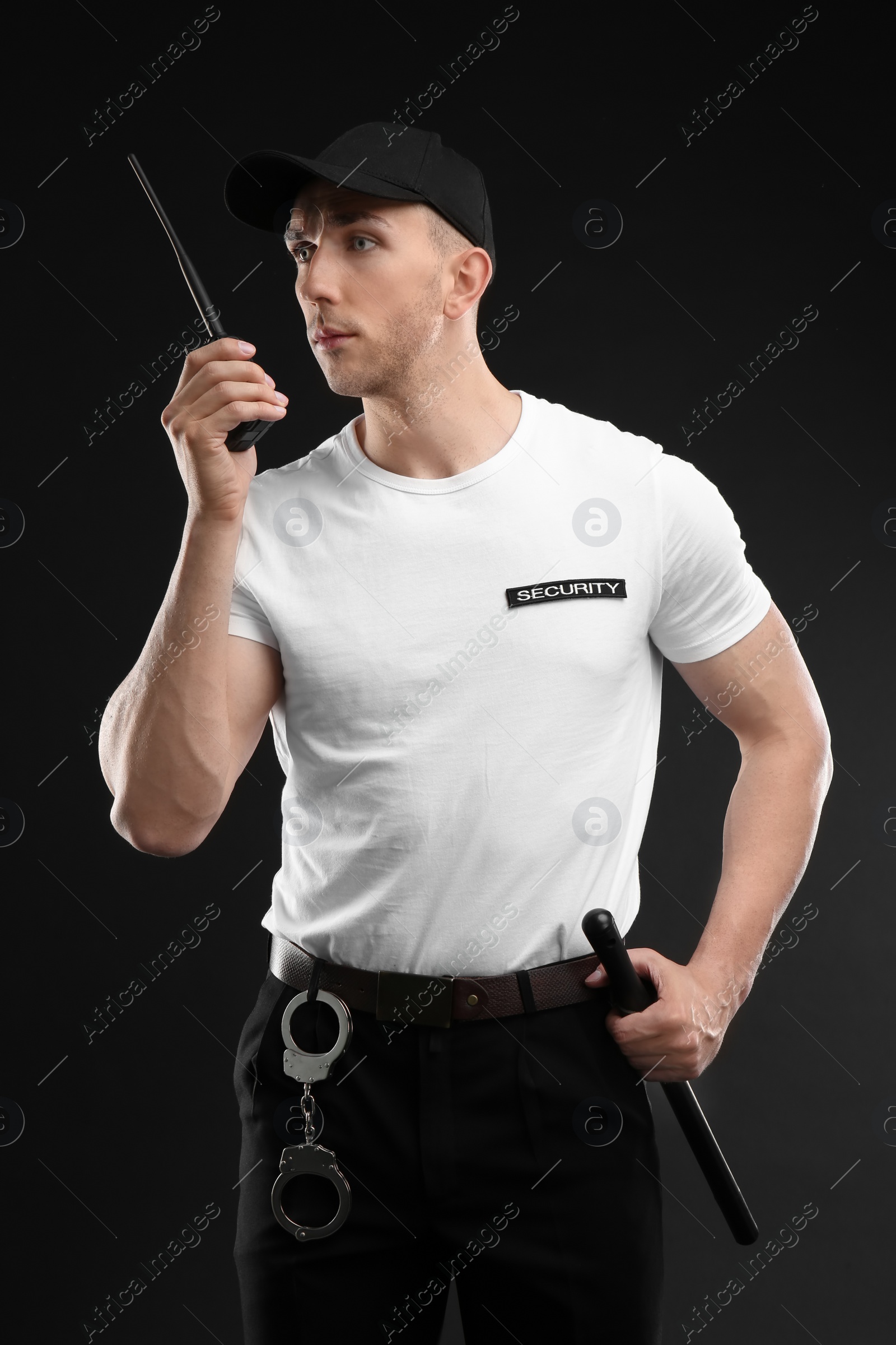 Photo of Male security guard using portable radio transmitter on dark background