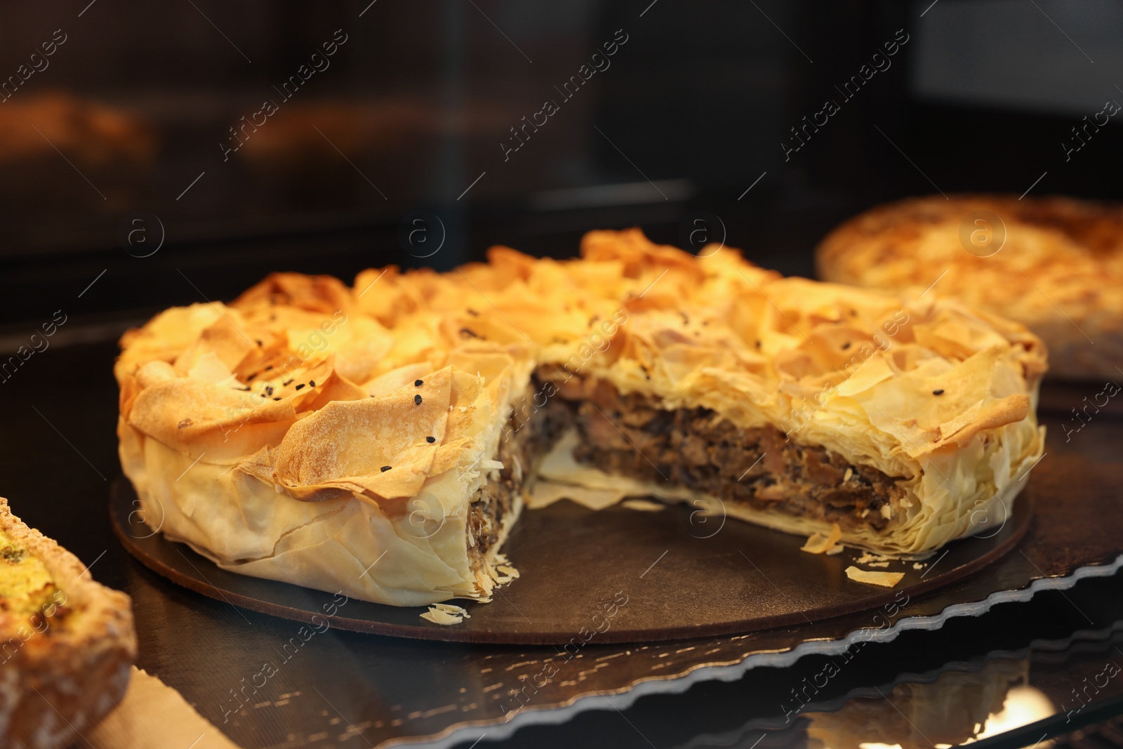 Photo of Delicious pie with mushrooms on counter in bakery shop, closeup. Space for text