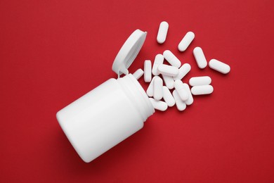 Photo of Antidepressants and medical bottle on red background, flat lay