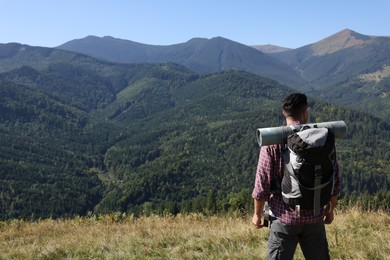 Photo of Tourist with backpack enjoying landscape in mountains on sunny day, back view