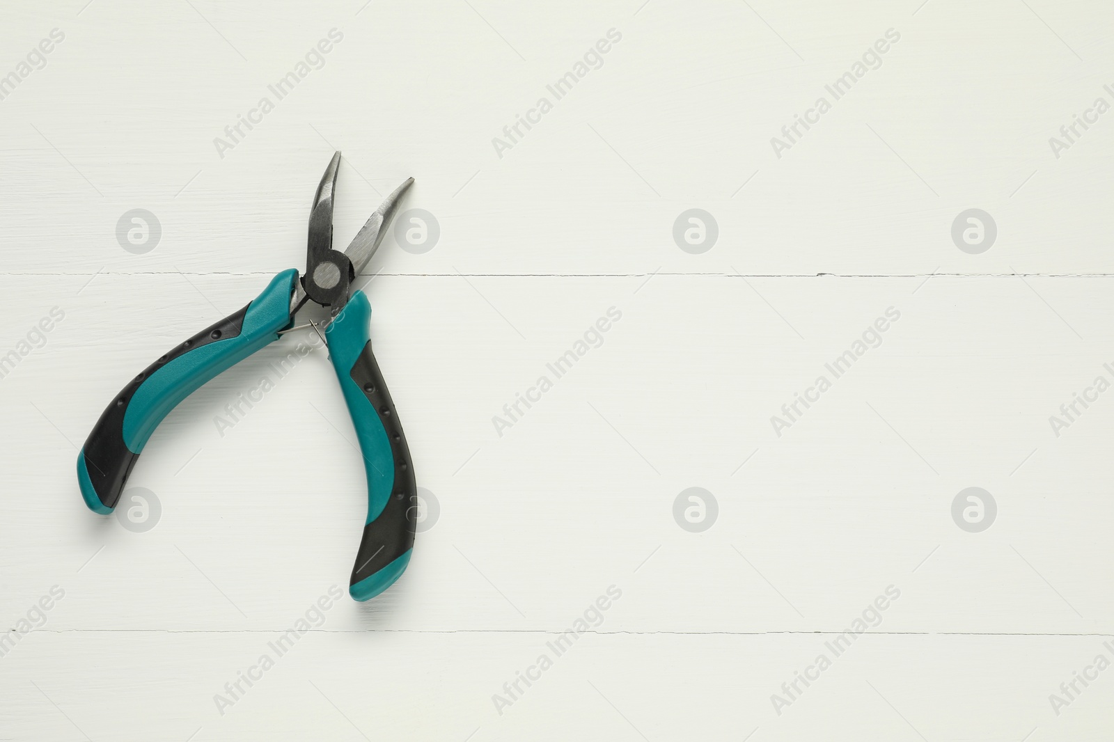 Photo of Bent nose pliers on white wooden table, top view. Space for text