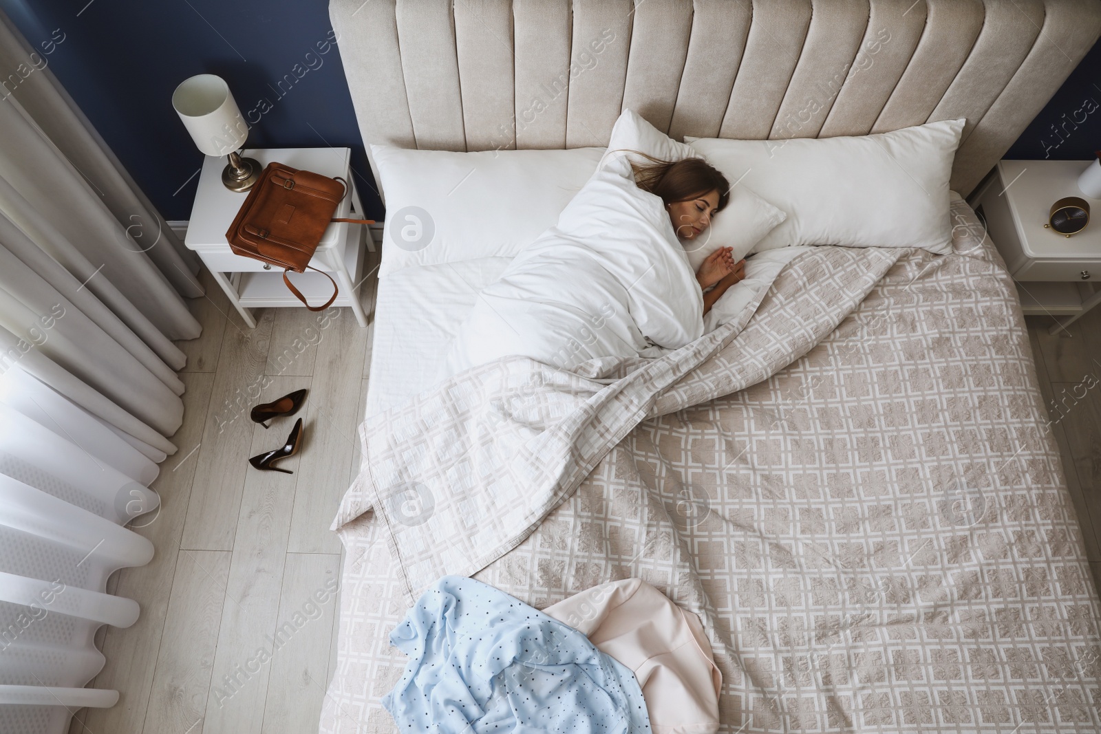 Photo of Tired woman sleeping in bed at home after work, above view