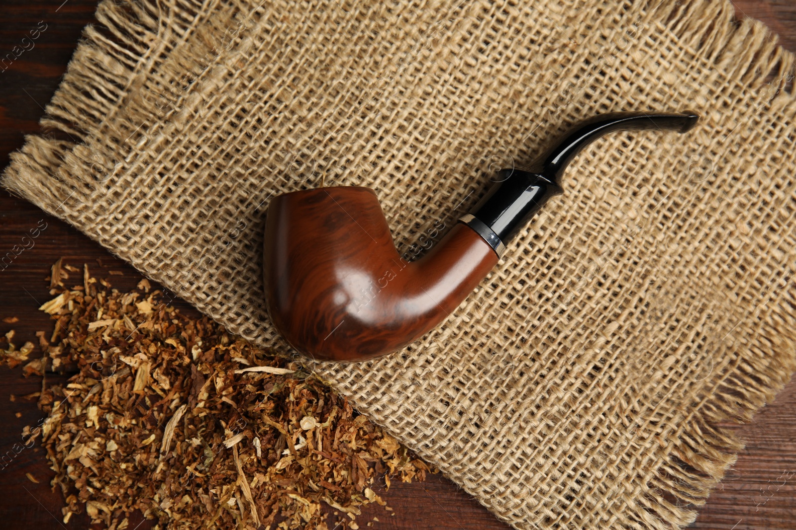 Photo of Classic smoking pipe with tobacco on wooden table, flat lay