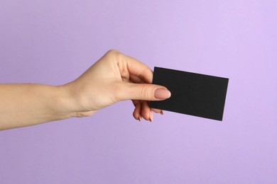 Photo of Woman with blank black business card on violet background, closeup. Mockup for design