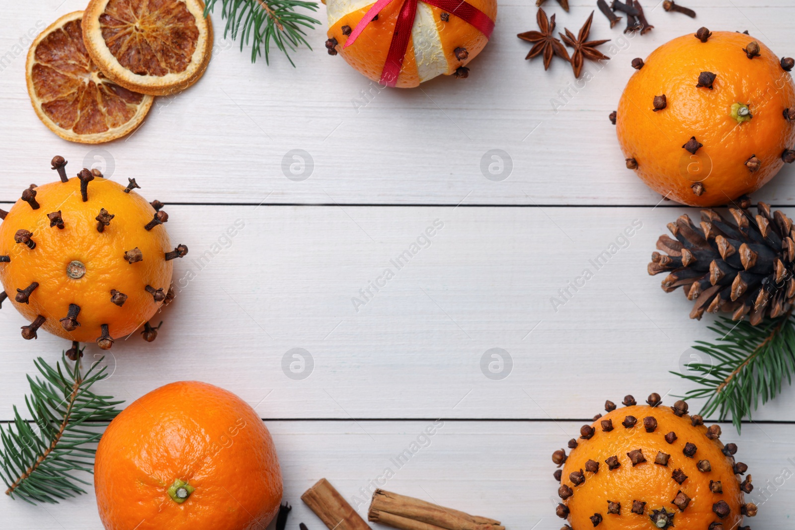 Photo of Pomander balls made of tangerines with cloves, spices and fir branches on white wooden table, flat lay. Space for text