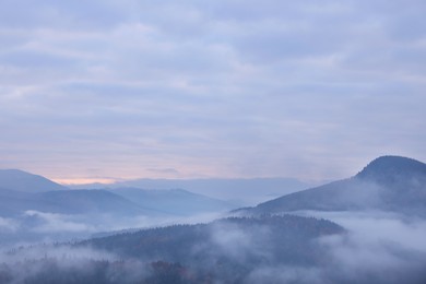 Photo of Beautiful view of mountains covered with fog and cloudy sky during sunrise