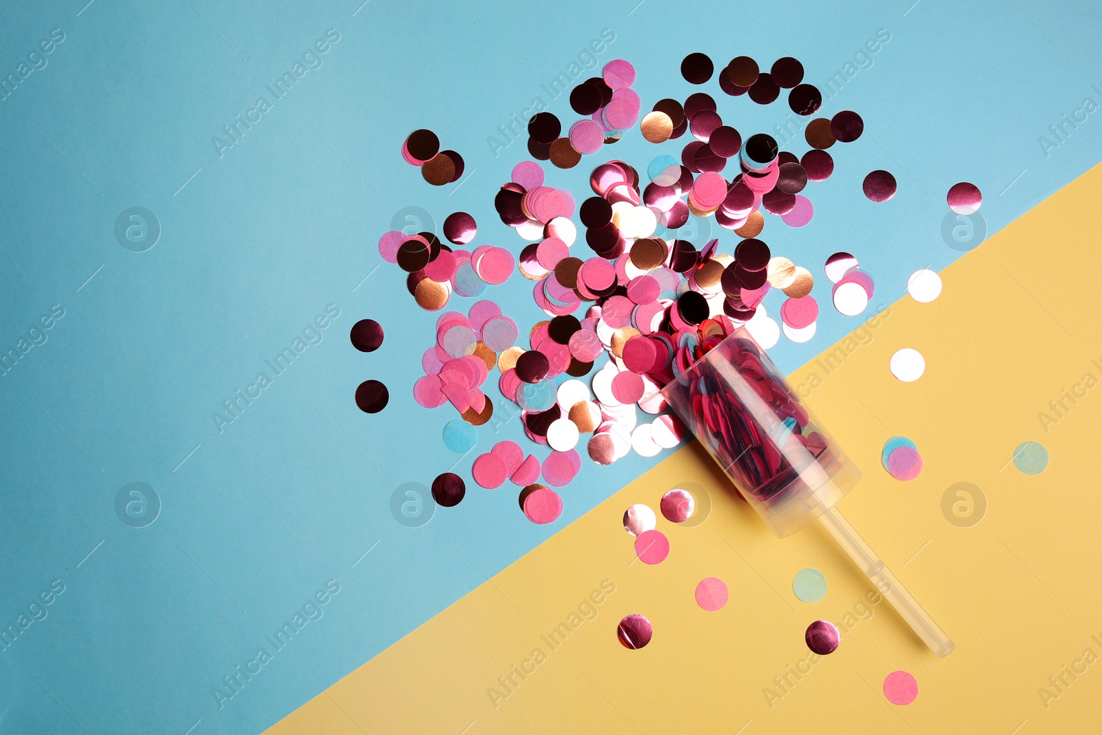 Photo of Party popper with pink confetti on color background, flat lay. Space for text