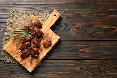 Photo of Branch with sweet dried dates on wooden table, top view. Space for text