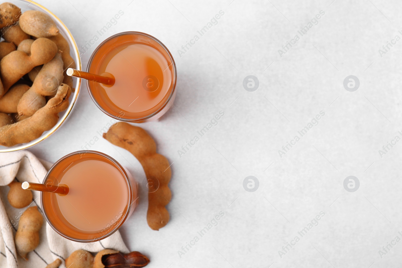 Photo of Tamarind juice and fresh fruits on white table, flat lay. Space for text