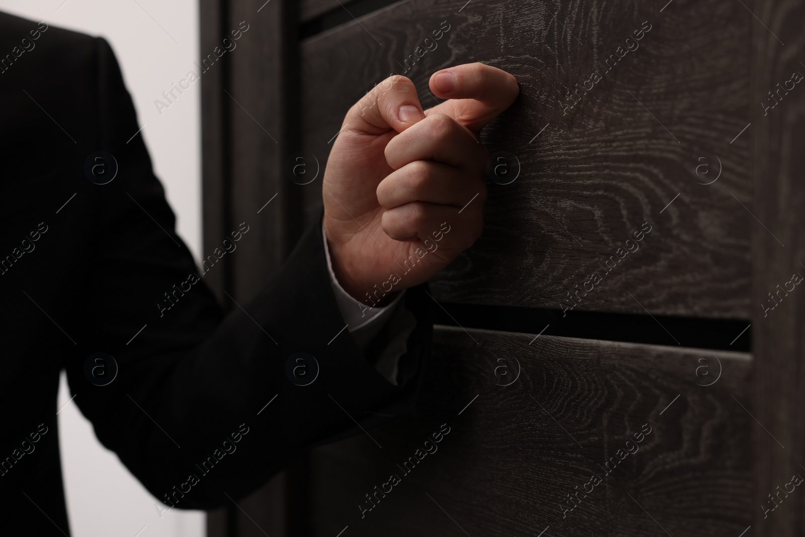 Photo of Collector knocking on door indoors, closeup view