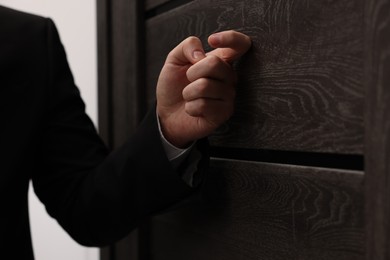 Photo of Collector knocking on door indoors, closeup view