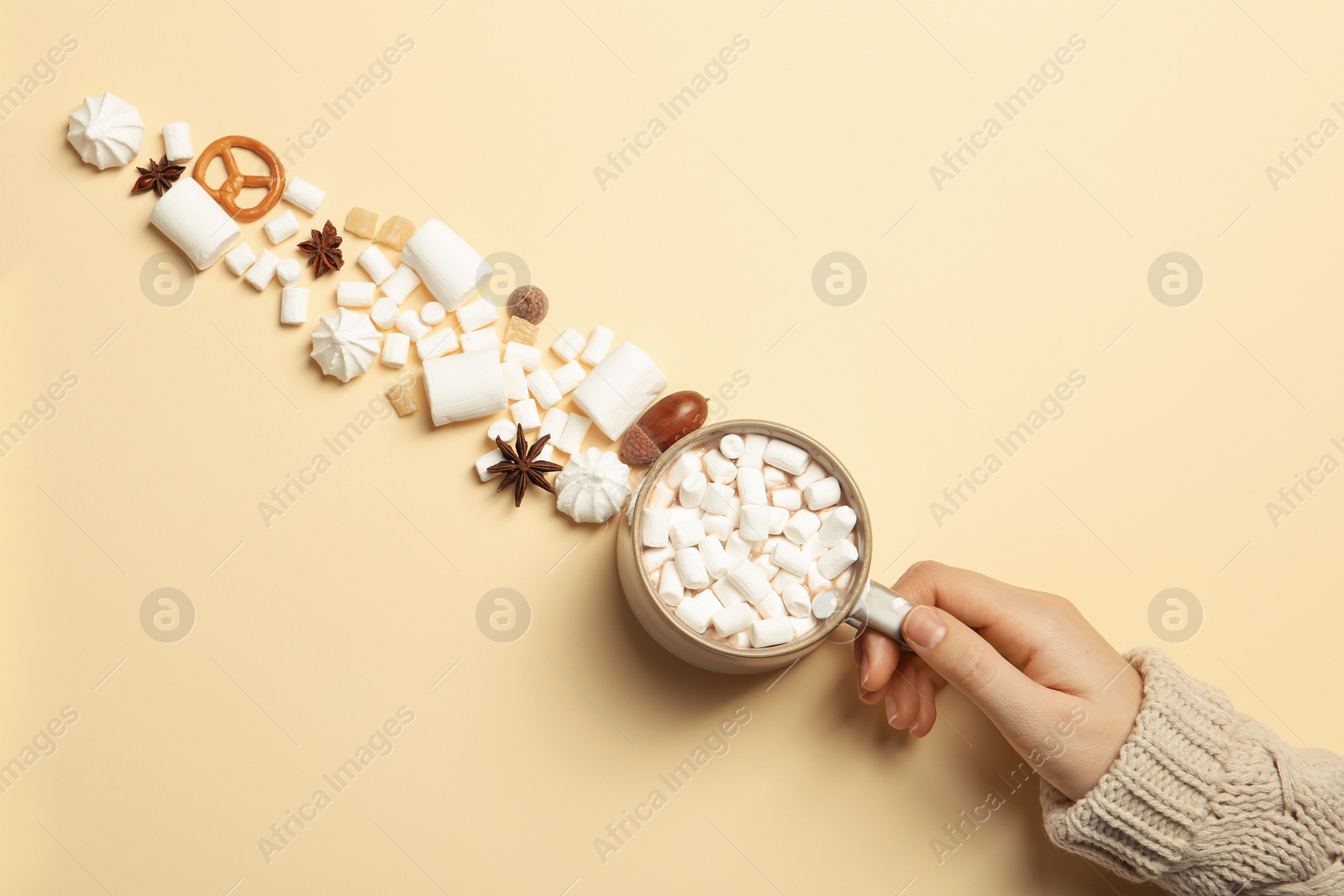 Photo of Woman in autumn sweater holding hot cozy drink on color background, top view