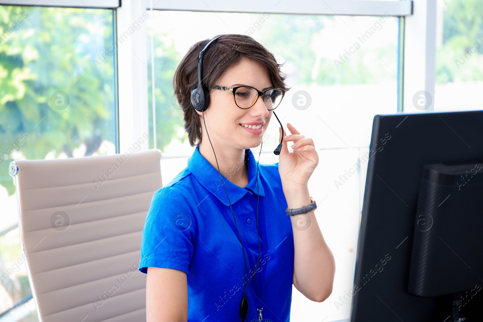 Photo of Female technical support operator with headset at workplace