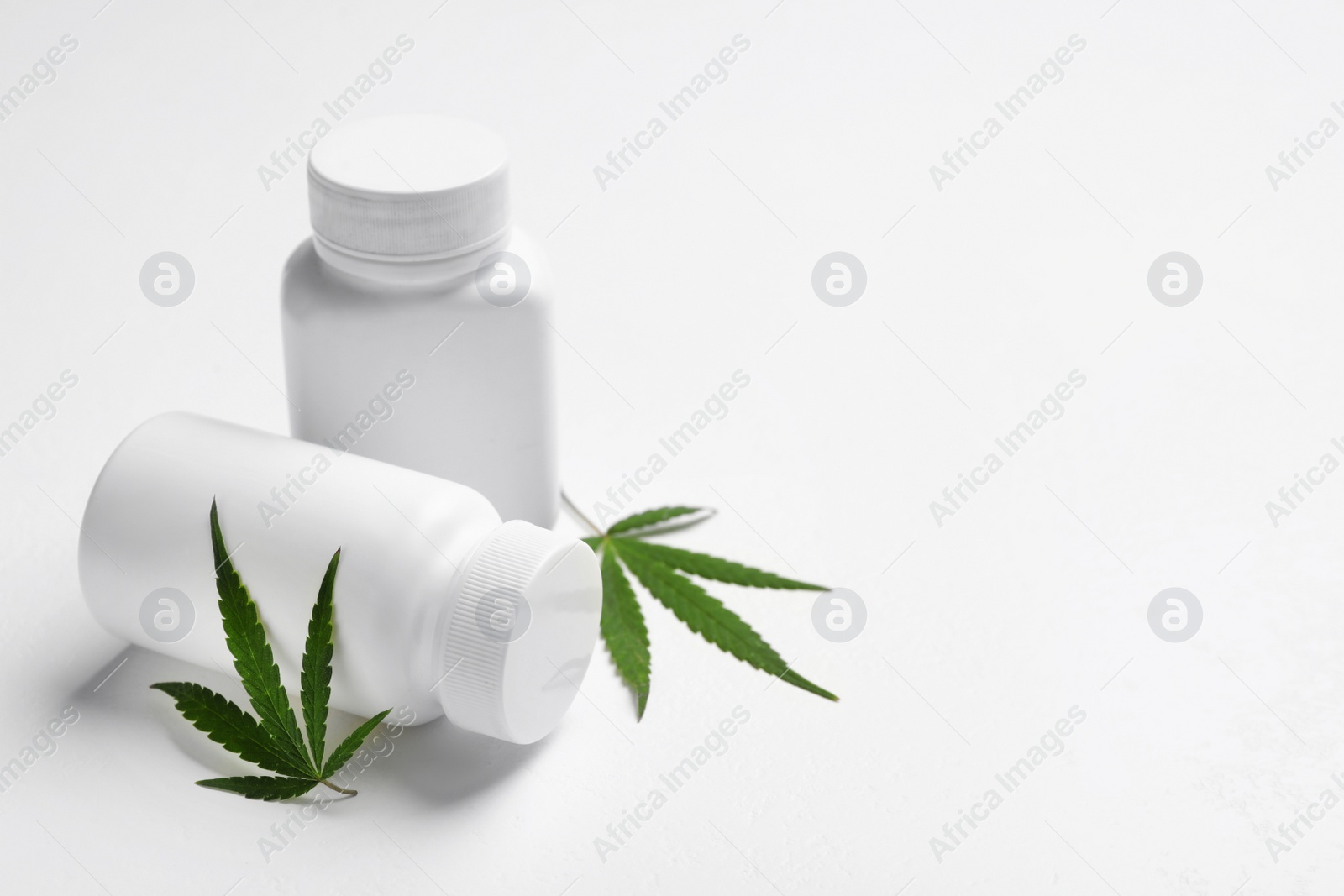 Photo of Hemp leaves and pill bottles on white background. Space for text