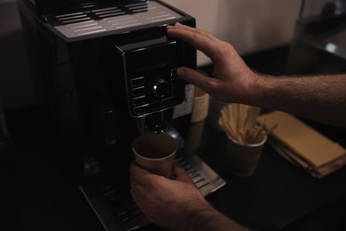 Photo of Barista preparing fresh aromatic coffee on modern machine, closeup