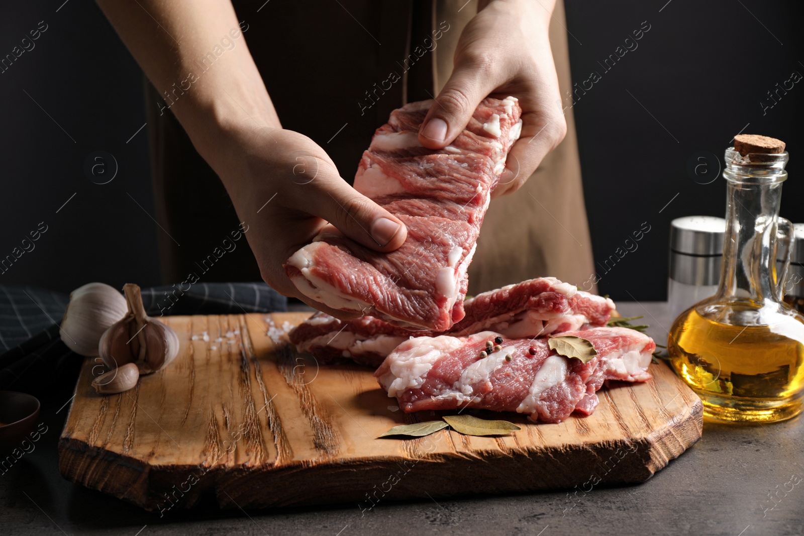 Photo of Man holding raw ribs at grey table, closeup