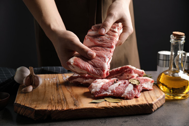 Photo of Man holding raw ribs at grey table, closeup