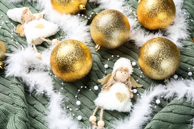 Photo of Composition with beautiful golden Christmas baubles on green knitted plaid, above view