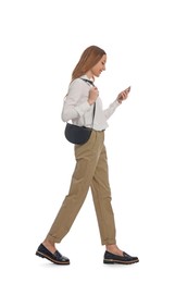 Young woman using smartphone while walking on white background