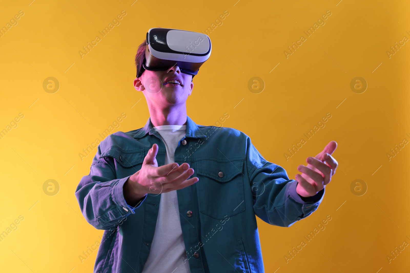 Photo of Young man with virtual reality headset on yellow background