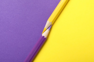 Two pencils on yellow and purple background, top view