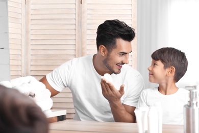 Photo of Father and son having fun while shaving in bathroom